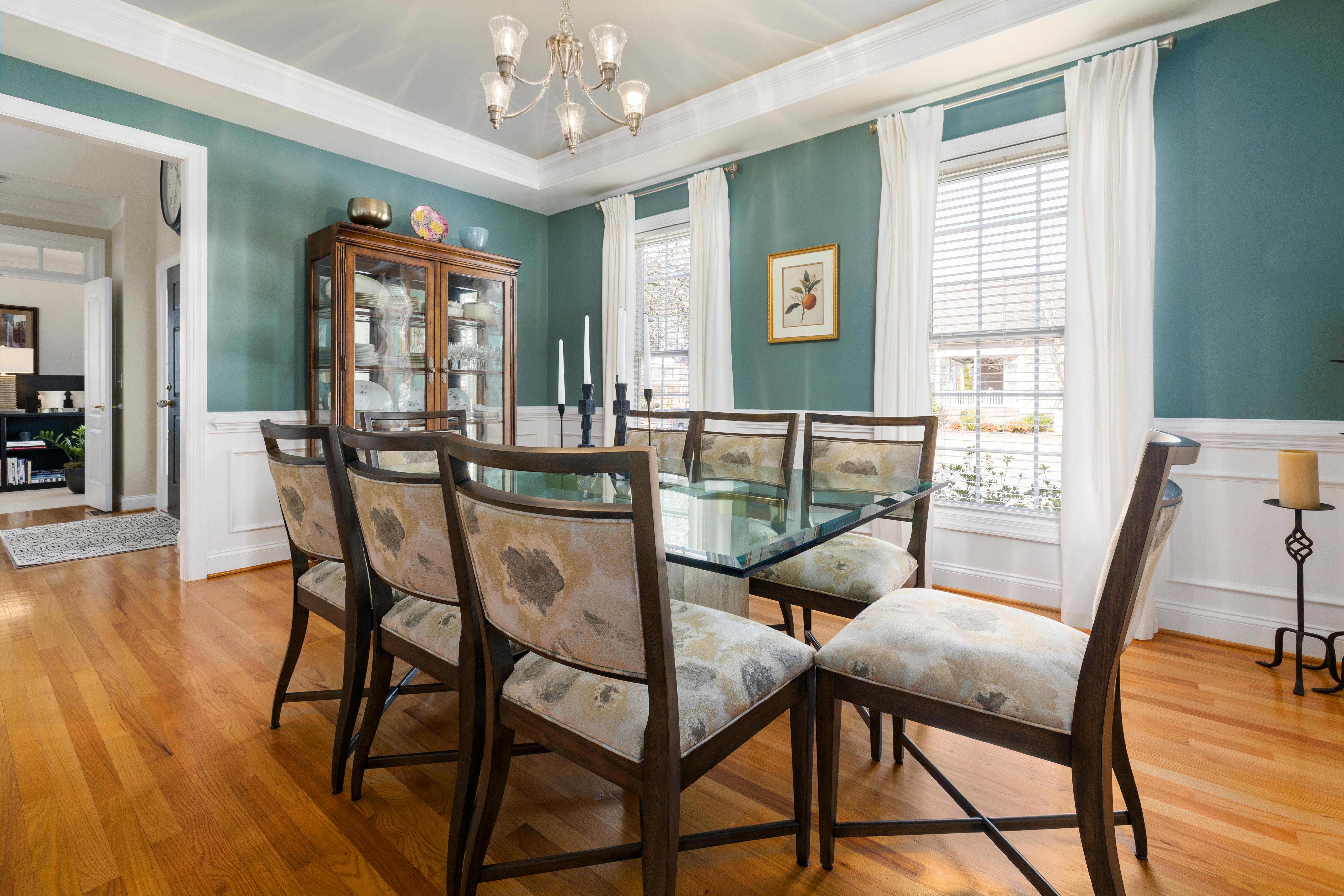Traditional dining room with teal walls, glass table, and china cabinet