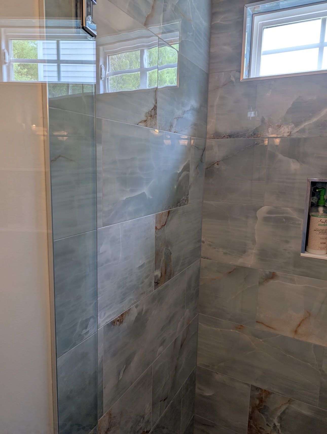 Modern shower with large format blue marble look tiles and glass enclosure