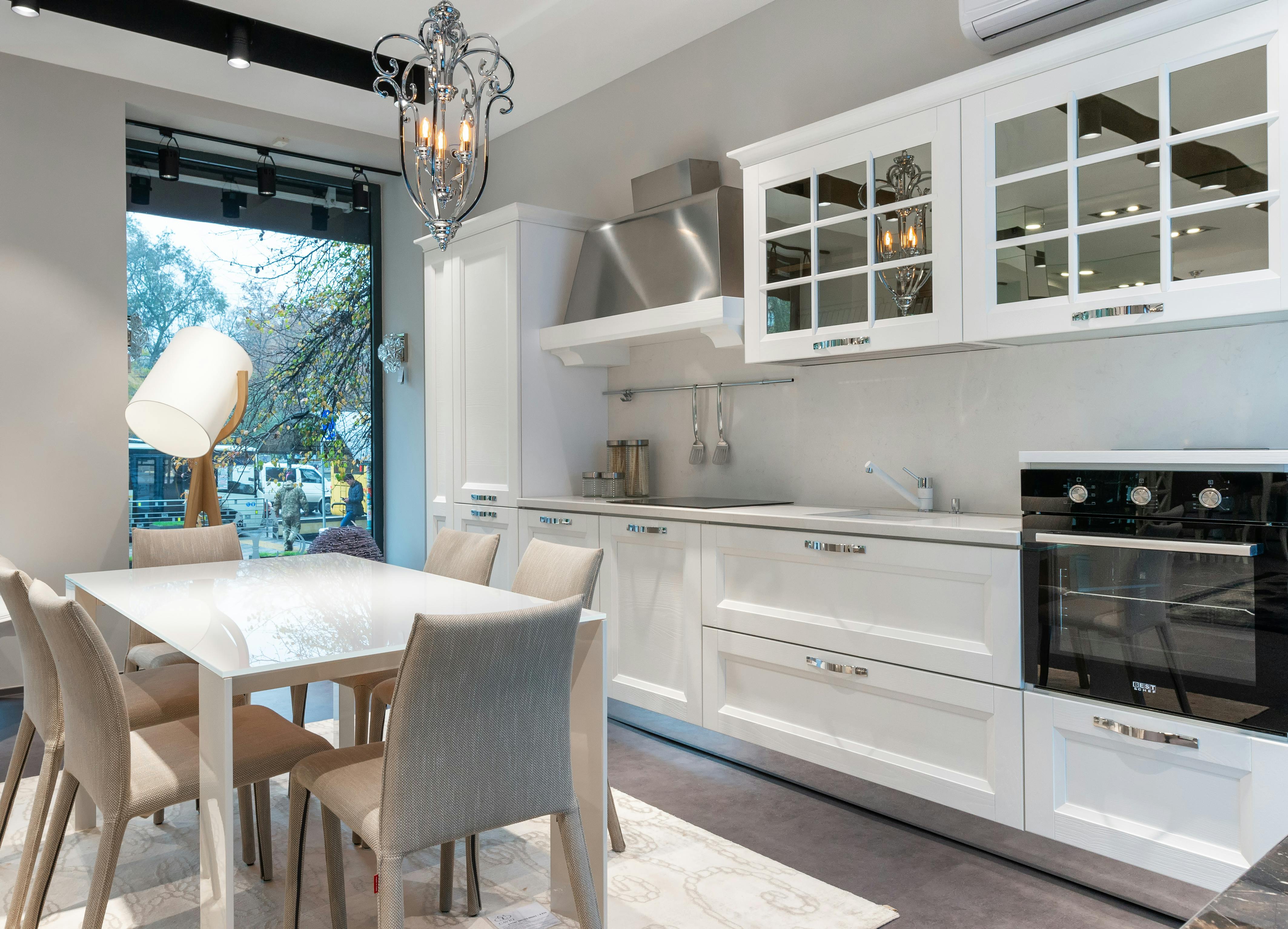 White kitchen and dining area with glass cabinets and stainless steel oven