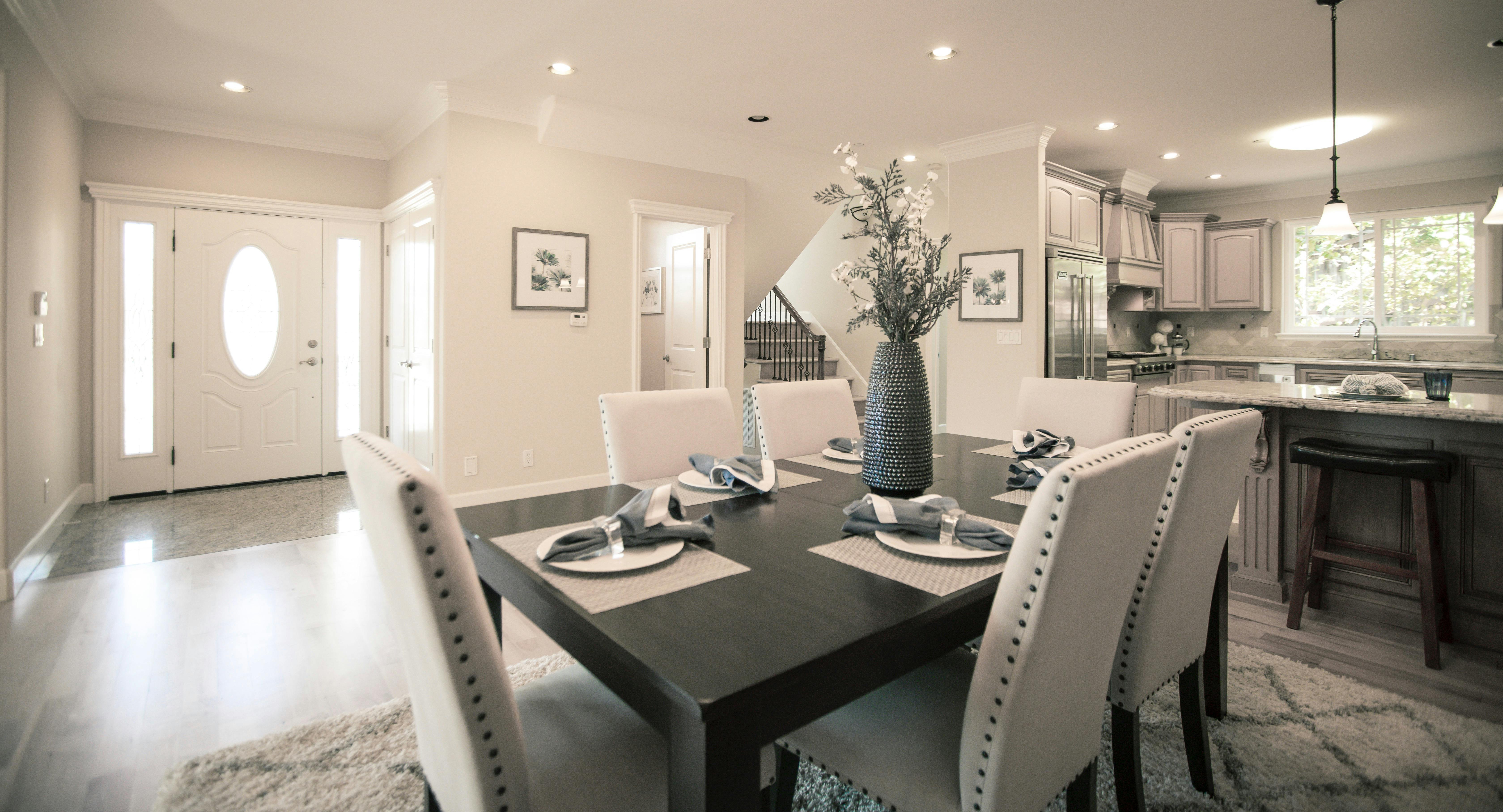 A modern dining room with a dark wood table and six beige upholstered chairs.