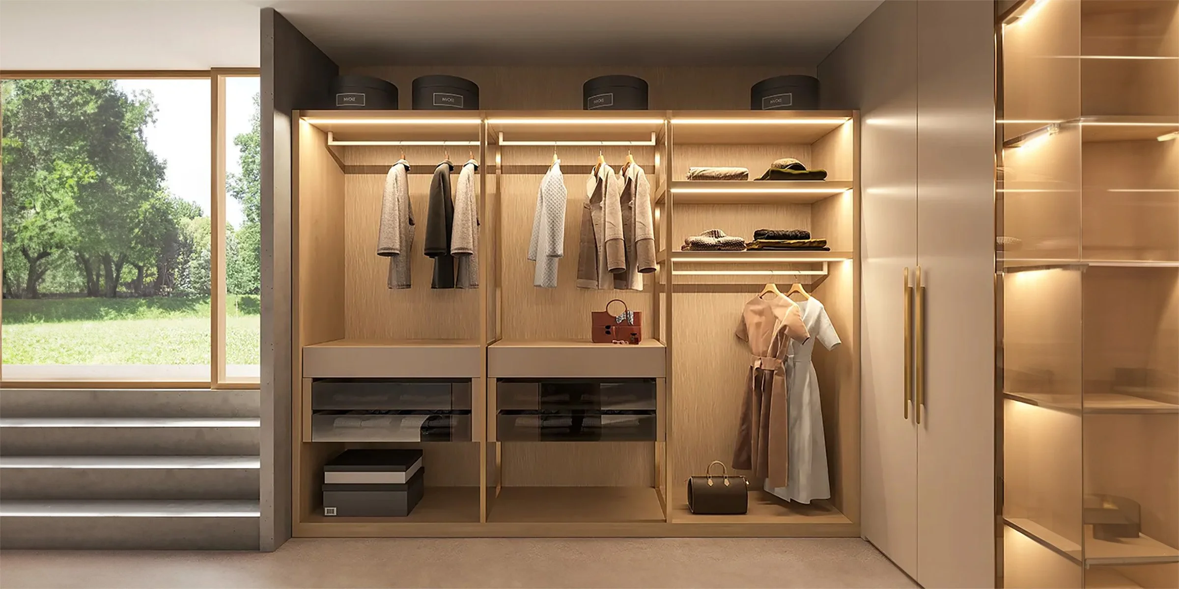 Modern walk-in closet with built-in wooden shelves and warm LED lighting, showcasing neatly hung clothes, folded garments, and luxury
 accessories near a large window overlooking a green outdoor view.